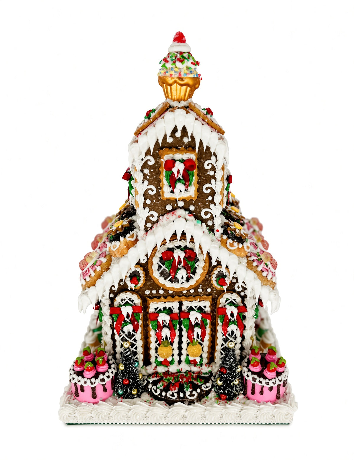 Front view of Sweet Savannah Gingerbread Chapel showing the cherry-topped cupcake spire, icicle-draped rooflines, wreath-decorated windows, and dessert-style medallion cookies lining the roof