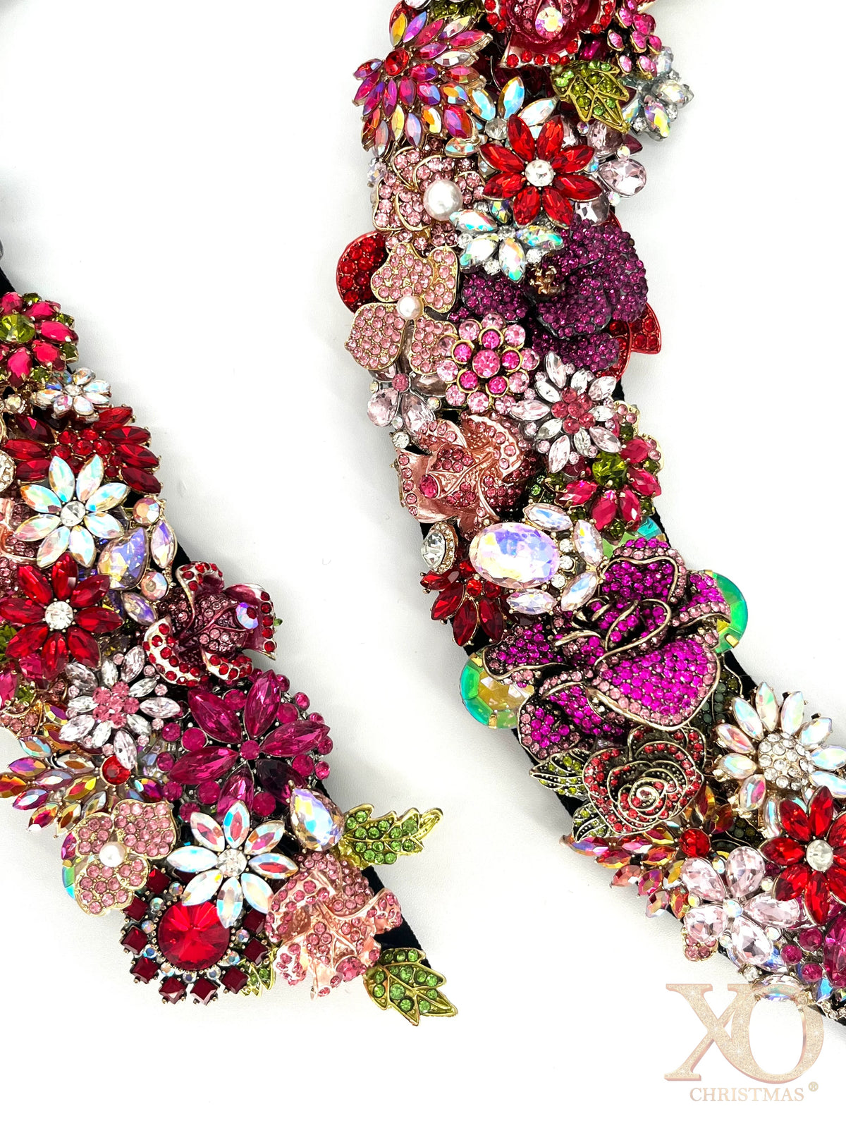 Close-up detail of jeweled wreath showing layered rhinestone florals, iridescent aurora borealis crystals, pink heart and butterfly embellishments, and a fuchsia rose in deep red, pink, and chartreuse