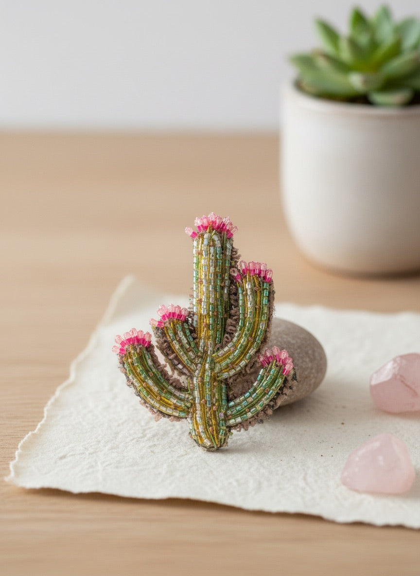 Hand-embroidered cactus brooch pin shaped like a saguaro with five arms, worked in vertical rows of green, gold, and pale aqua beads, each arm topped with a crown of hot pink beaded blooms.