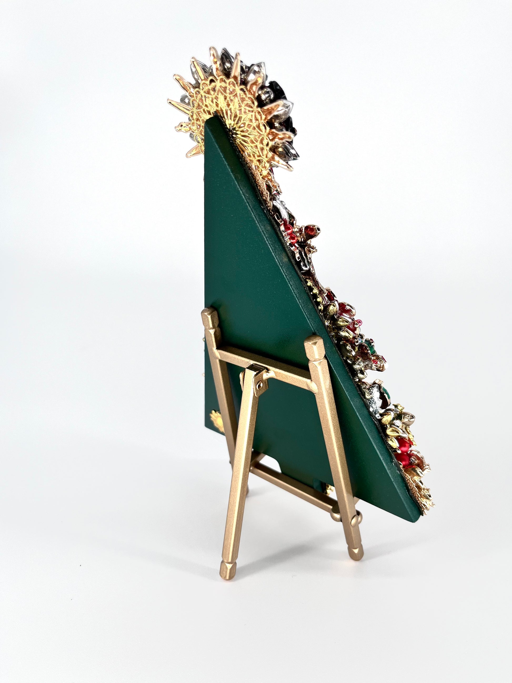 Side view of Christmas tree jeweled art showing green backing displayed on gold easel 
