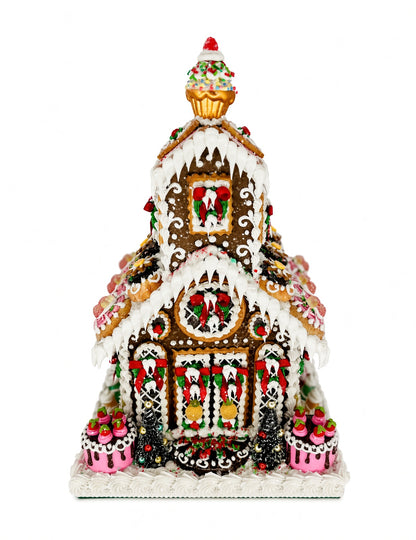 Front view of Sweet Savannah Gingerbread Chapel showing the cherry-topped cupcake spire, icicle-draped rooflines, wreath-decorated windows, and dessert-style medallion cookies lining the roof