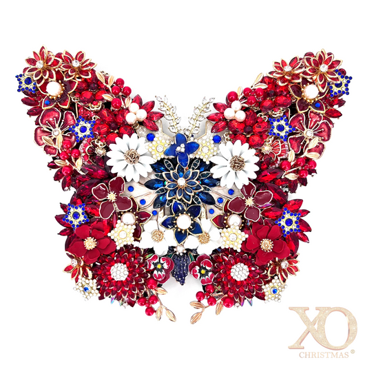 A highly detailed, symmetrical butterfly-shaped jeweled  decorative piece composed of red, white, and blue floral elements with gold-toned metal settings, shown against a plain white background.