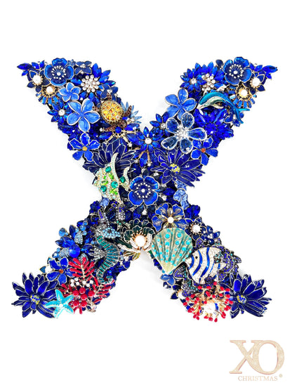 Sapphire blue rhinestone jeweled letter X with a dolphin, sea turtle, starfish, and coral fish detail, accented with faux pearl centers and coral red and gold tones