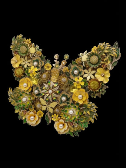 Sunshine Flight jeweled butterfly wall art at a slight angle against a black background, showing dimensional depth — composed of yellow flowers, green leaves, and a dense arrangement of jeweled accents and pearl-like centers. Handmade in the USA.