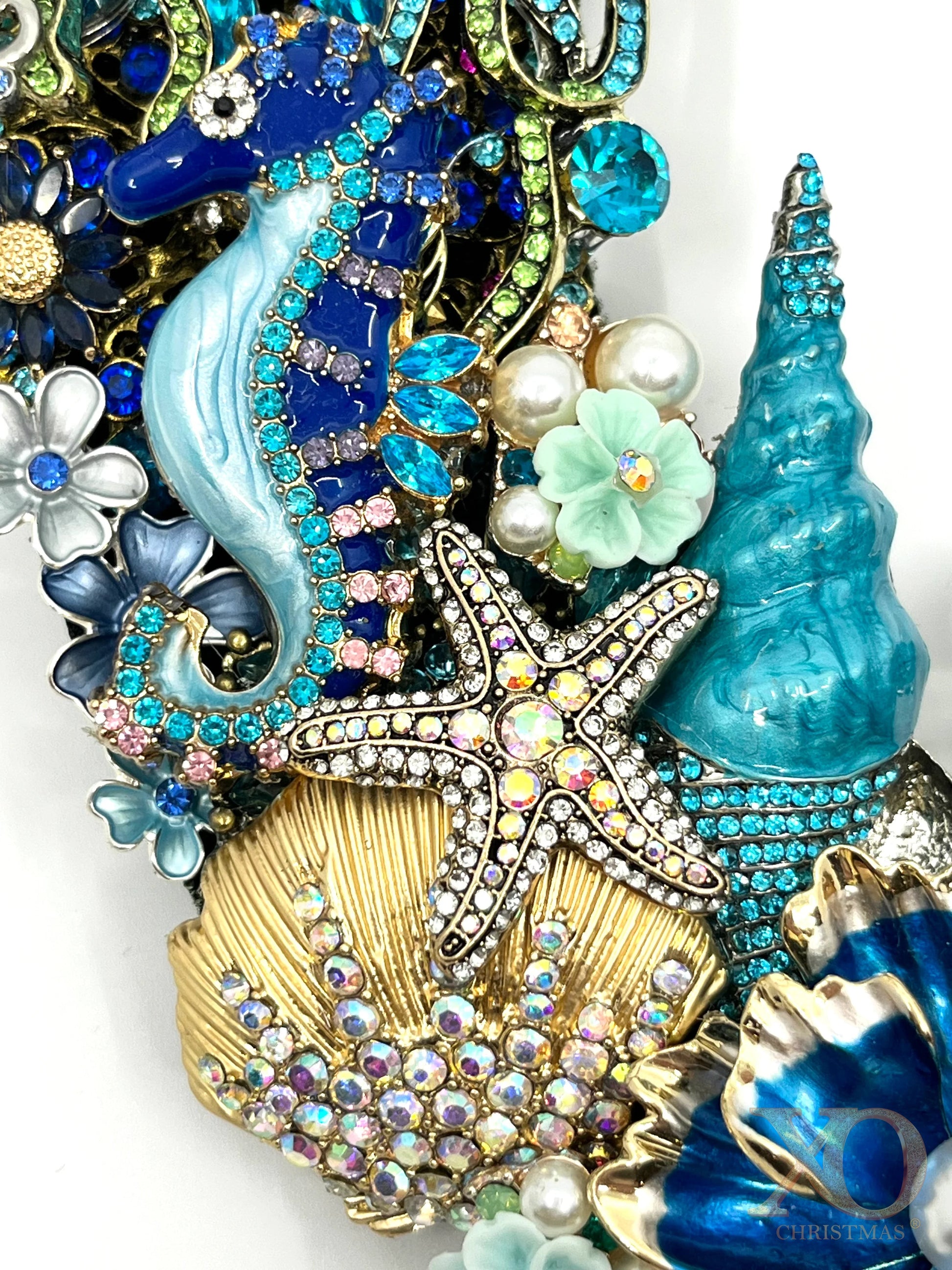Close-up of a coastal jeweled wreath with a sapphire-blue seahorse, rhinestone starfish, gold shell and turquoise coral details.