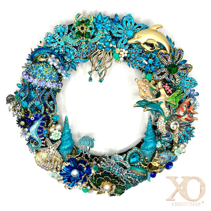 Handmade coastal Christmas wreath of blue and gold jeweled brooches shaped into dolphins, seahorses, starfish, shells and coral.