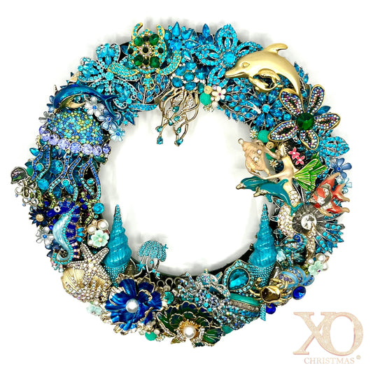 Handmade coastal Christmas wreath of blue and gold jeweled brooches shaped into dolphins, seahorses, starfish, shells and coral.