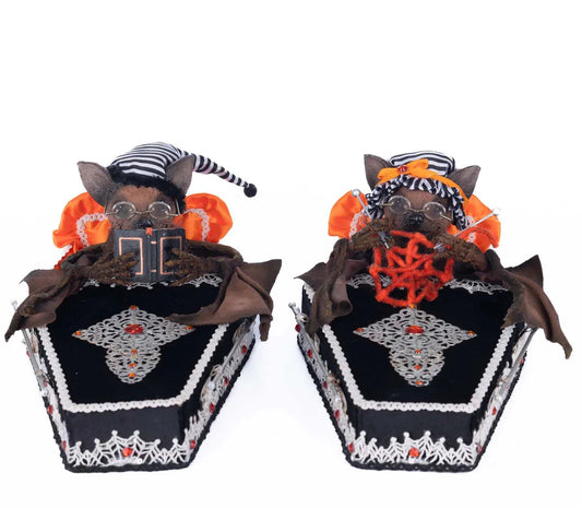 Bedtime with the Batsons bat coffin figurine pair — two dressed bat characters with glasses and orange wings resting in jeweled black velvet coffins with silver filigree and paper doll trim, on a white background.