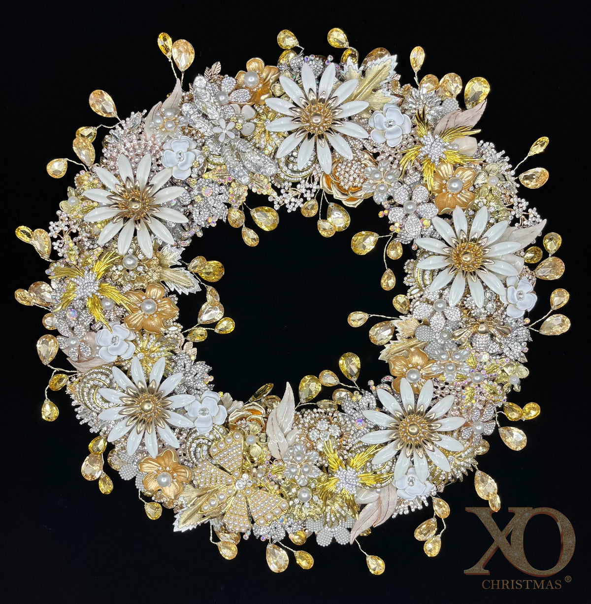  Jeweled wreath densely layered with white enamel daisy brooches, shades of gold and champagne floral clusters, faux pearl flowers, and faceted champagne teardrop rhinestones against a black background.