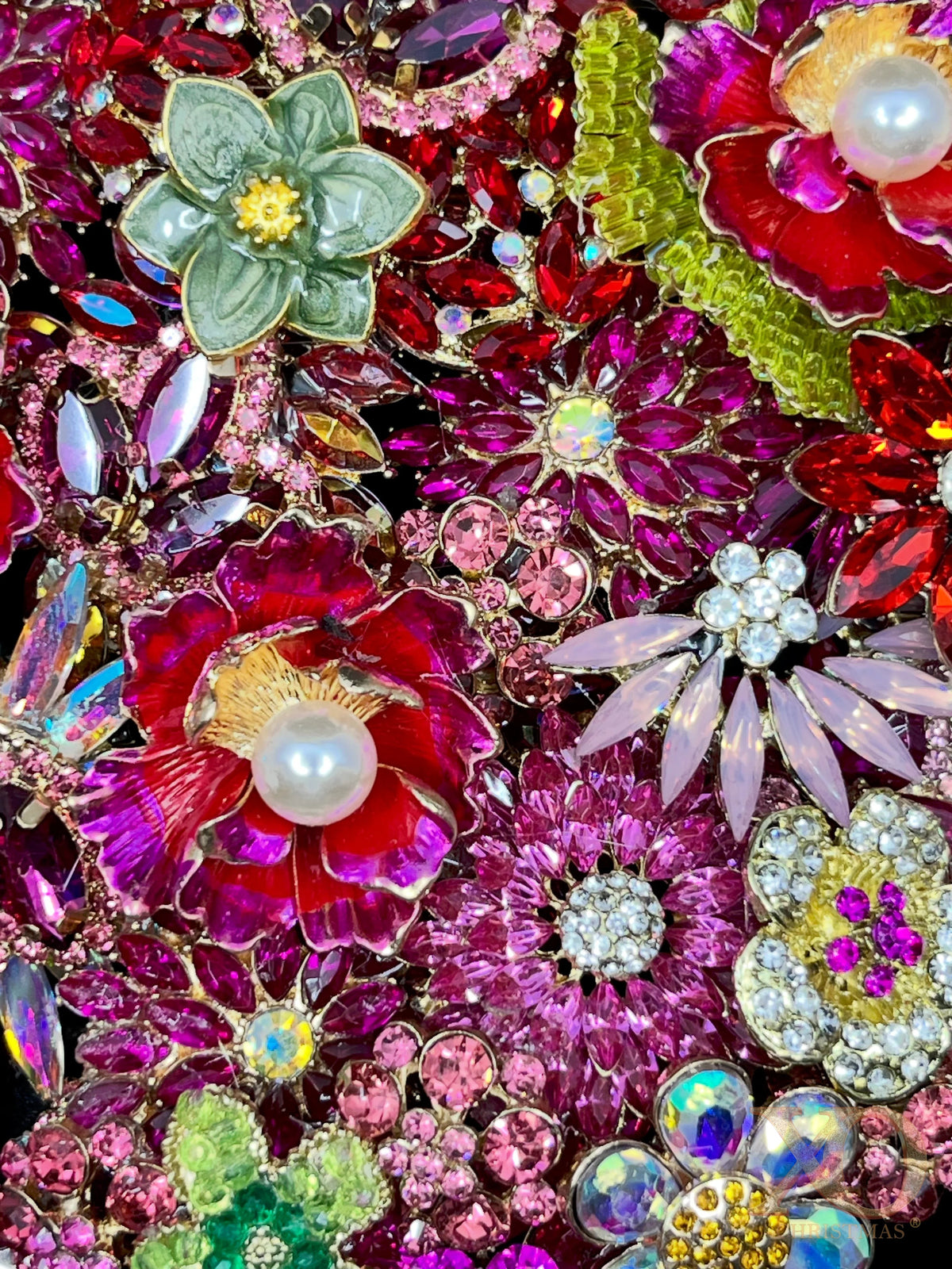 Close-up of Pink Jeweled Butterfly Sculpture featuring layered floral brooches with pearl centers, fuchsia and magenta rhinestones, sage green enamel flower accents, and aurora borealis rhinestones.