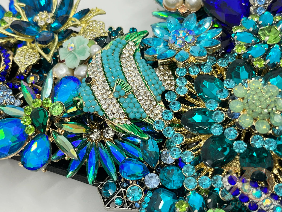 Close-up of a heavily jeweled ocean wreath featuring a tropical fish crafted from teal and crystal rhinestones