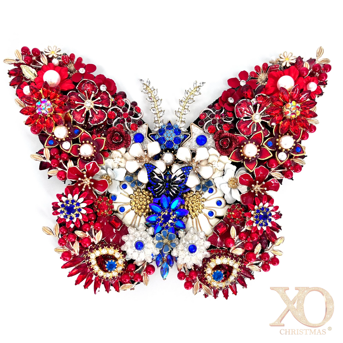 A highly detailed, symmetrical butterfly-shaped jeweled  decorative piece composed of red, white, and blue floral elements with gold-toned metal settings, shown against a plain white background. 