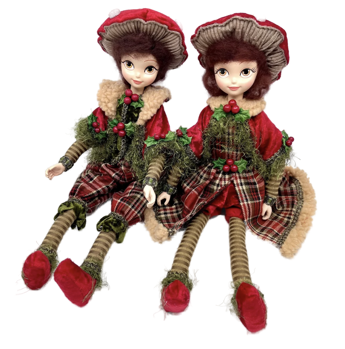 Two seated boy and girl shelf sitter figures in red mushroom caps with tan ribbed undersides, auburn hair, and amber eyes, wearing sherpa collars, red capes with moss-green fringe, holly and red berry accents, red tartan plaid, striped stockings, and red slippers.