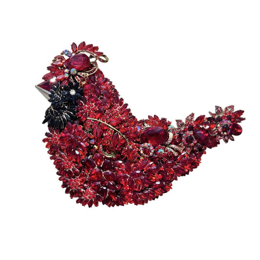 Suggestion


A vintage-style bird brooch embellished with numerous red and dark red faceted rhinestones, set in gold-tone metal with a small black floral accent on the side, shown against a plain white background. Handmade in the USA
