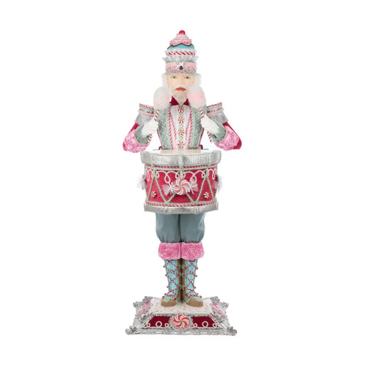 Katherine's Collection Commander Cupcake Nutcracker Server on a plain white background, showing full front view — layered cake hat, cotton candy-style pink cuffs, a red peppermint-patterned drum, rose-trimmed boots, and an ornate silver pedestal base.