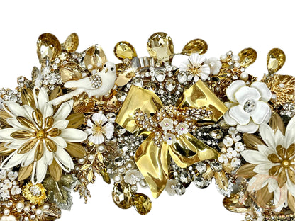 Close-up of vintage polished gold bow and ivory jeweled wreath showing a jeweled white dove, white enamel flowers, faux pearls, and champagne crystal drops