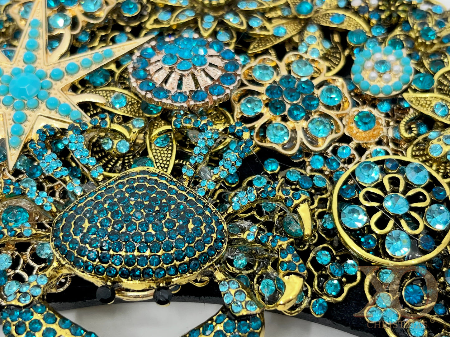Close-up of Deep Blue coastal jeweled wreath showing a turquoise crab, gold starfish, seashell, and blue rhinestone flower brooches.