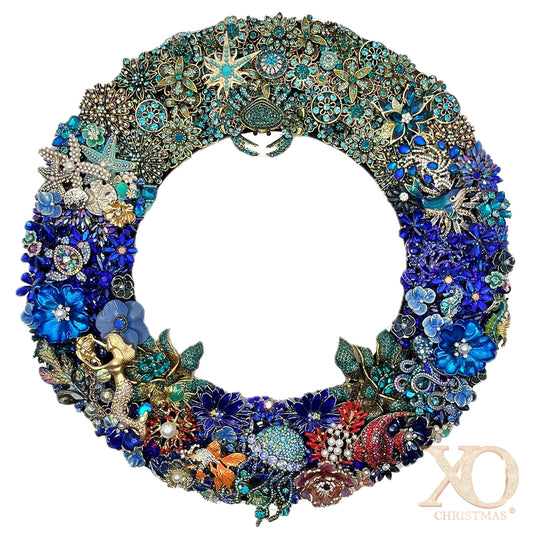 Deep blue jeweled coastal Christmas wreath covered in crab, coral fish, and starfish brooches in shades of blue, teal, and gold.